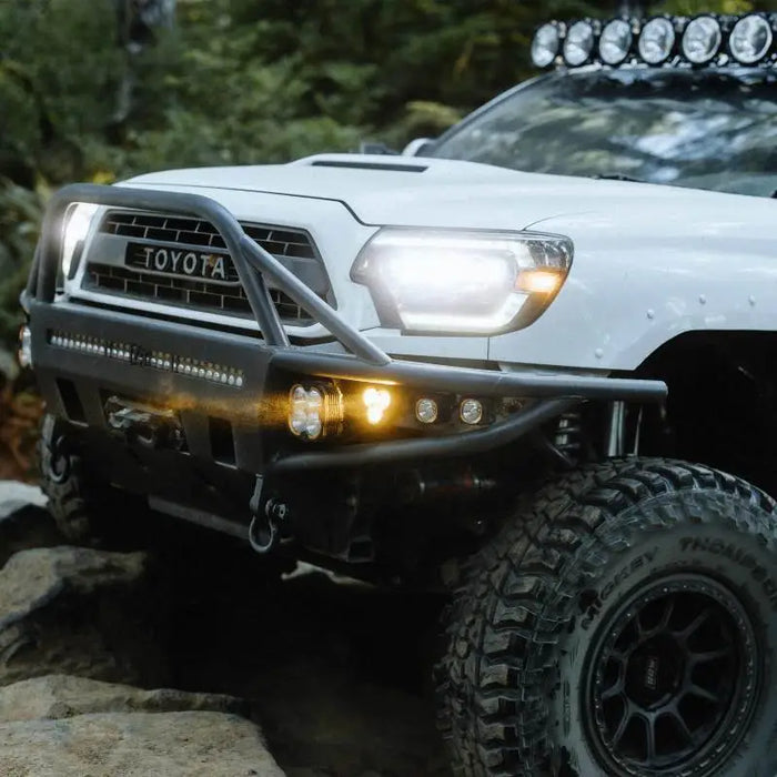 White truck driving on rocky trail, KC HiLiTES FLEX ERA 3 Dual Mode SAE Fog Lights.