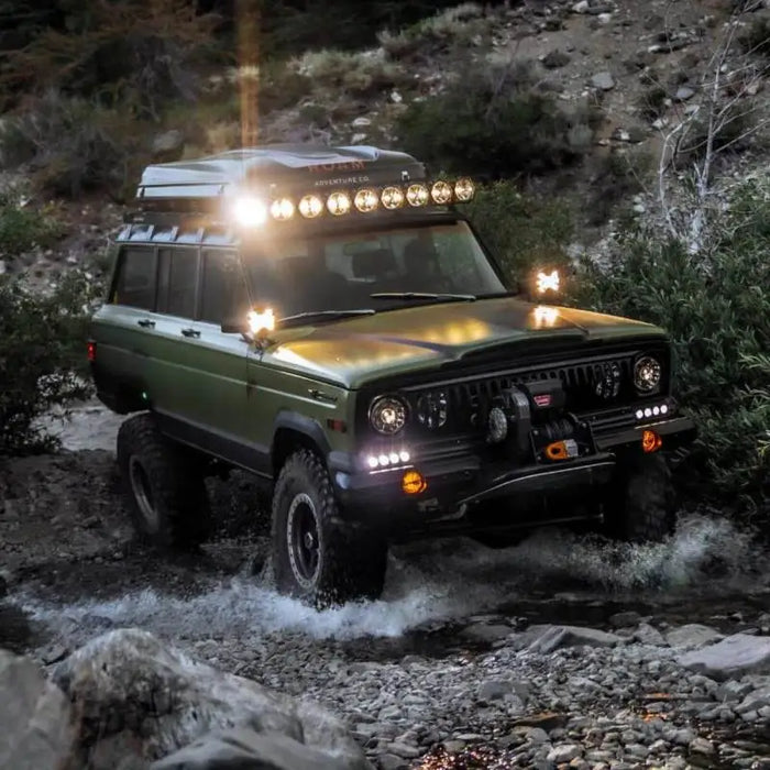 SlimLite LED lights on green jeep crossing rocky river.