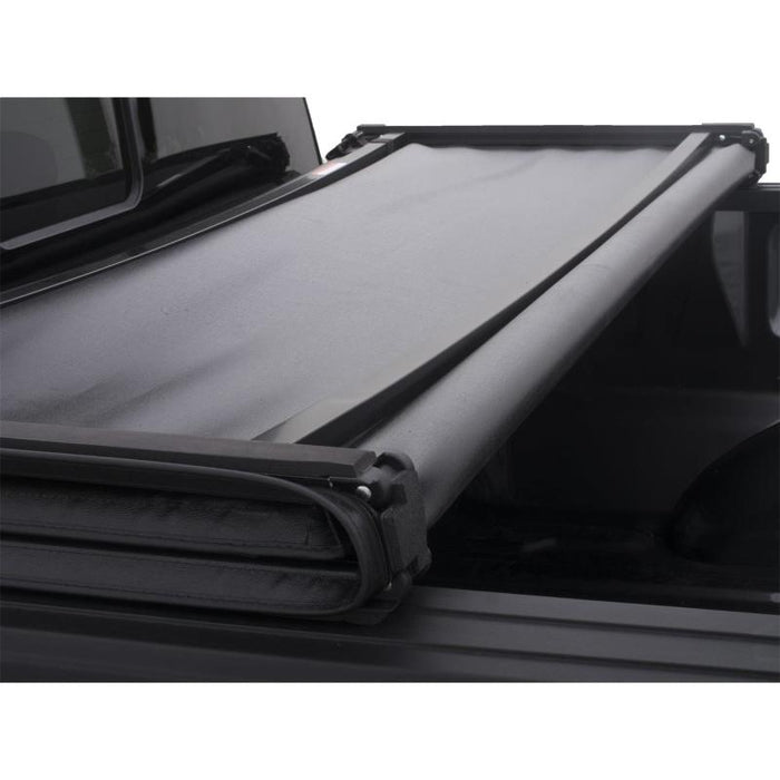 Black lund genesis tri-fold tonneau cover on toyota tacoma bed with roll bar
