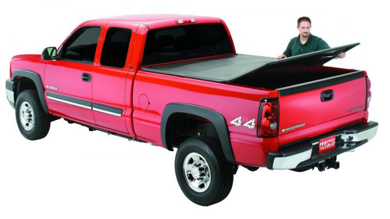 Man standing next to black lund tri-fold tonneau cover for toyota tacoma truck