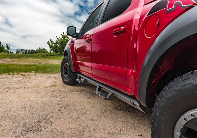 Red truck parked on dirt road near n-fab epyx 07-18 jeep wrangler jk 4dr suv - cab length - tex. Black