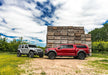 Two red trucks parked in front of a wooden cabin, suitable for jeep wrangler jk