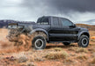 Black toyota tacoma double cab driving through desert, showcasing n-fab nerf steps cab length in black w2w 2in