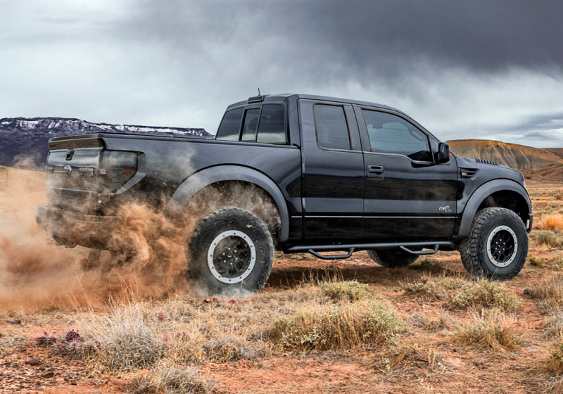 Black toyota tacoma double cab driving through desert, showcasing n-fab nerf steps cab length in black w2w 2in