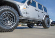 White jeep with large tire featuring n-fab rock rails for 2018 jeep wrangler jl 4 door - gloss black