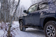 Blue jeep driving on snowy road with n-fab trail slider steps in textured black for toyota 4runner