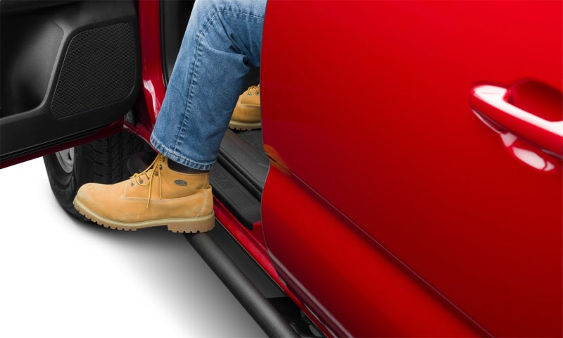 Man in jeans and yellow shoes stepping on red truck steps from n-fab trail slider steps for toyota tacoma crew cab in textured black