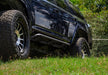 Black jeep wrangler parked in grass with n-fab trailslider steps in textured black