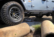 N-fab trail slider steps for jeep wrangler jl 4 door suv with big tire and rocks in textured black