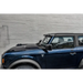 Blue Land Rover parked in front of brick wall next to Oracle 2021+ Ford Bronco Integrated Windshield Roof LED Light Bar System.