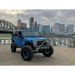 Dynamic blue jeep with oversized tire, featuring Oracle 7in High Powered LED Headlights.