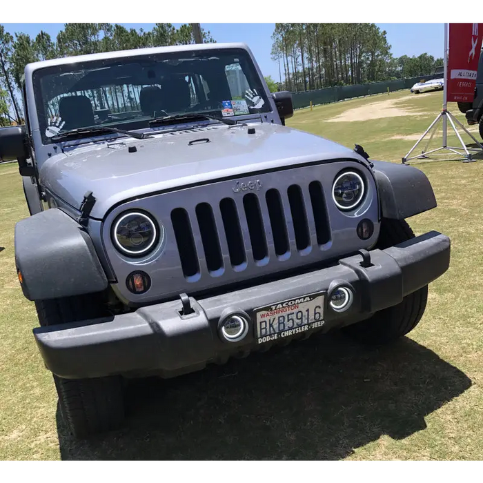 Gray Jeep parked in field with Oracle 7in High Powered LED Headlights in Black Bezel and White color.