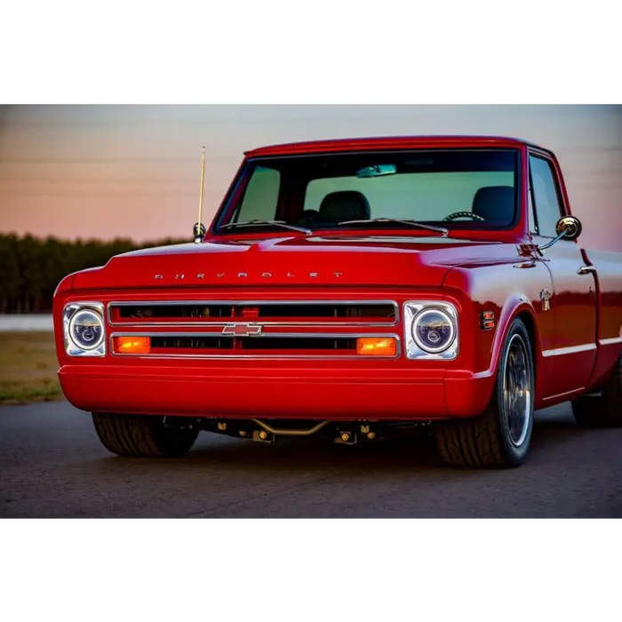 Red truck parked on road next to Oracle 7in LED headlights - black bezel - white