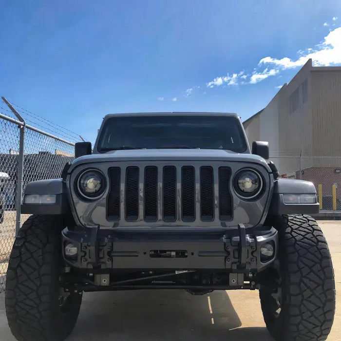 Oracle Jeep Wrangler JL/Gladiator JT Sport with LED fog lights parked in a lot with fence.