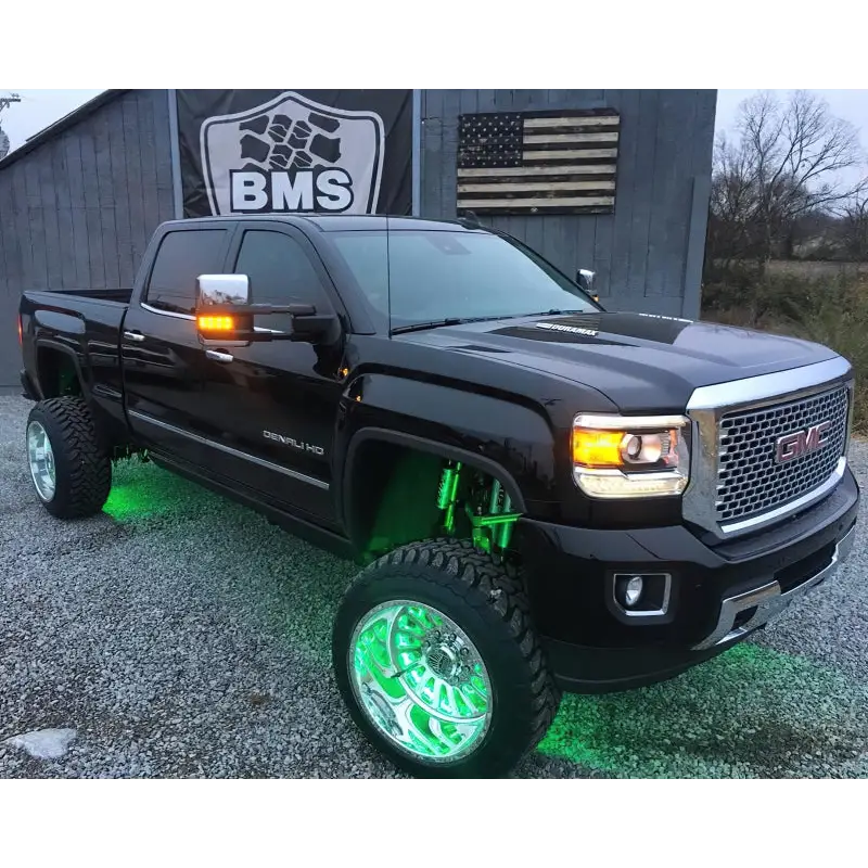 Green LED illuminated wheel rings on an off-road truck parked in front of a building.