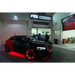 Red LED illuminated wheel rings kit with car parked in front of a building