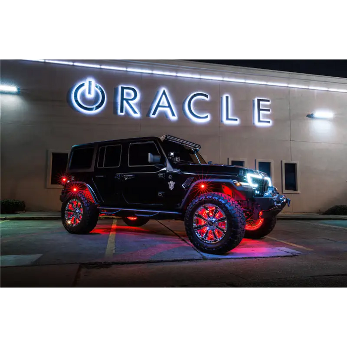 Close up of red double LED Oracle LED Illuminated Wheel Rings kit displayed on a parked jeep in front of a building