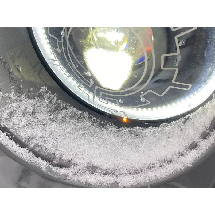 Close up of snow-covered car wheel on a Jeep Wrangler with Oracle Lighting Oculus Bi-LED Projector Headlights.