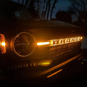LED letter badges on car with headlights on at night