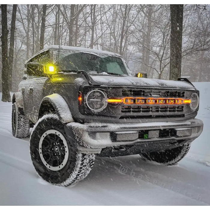 Truck driving through snow with LED letter badges.