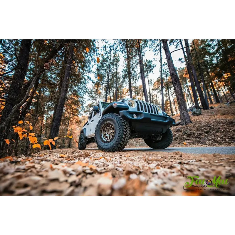 Close-up of Jeep parked in woods on dirt road with Oracle Oculus Bi-LED Projector Headlights for Jeep JL/Gladiator JT - Matte Black - 550