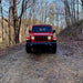 Red Jeep with Oracle Oculus Bi-LED Projector Headlights parked on dirt road.