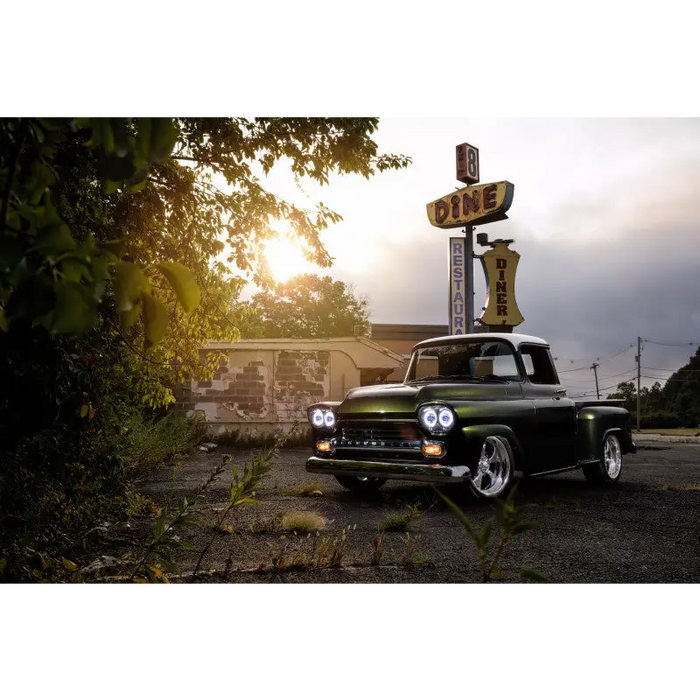 Green truck parked in front of a building with oracle pre-installed sealed beam halo headlights