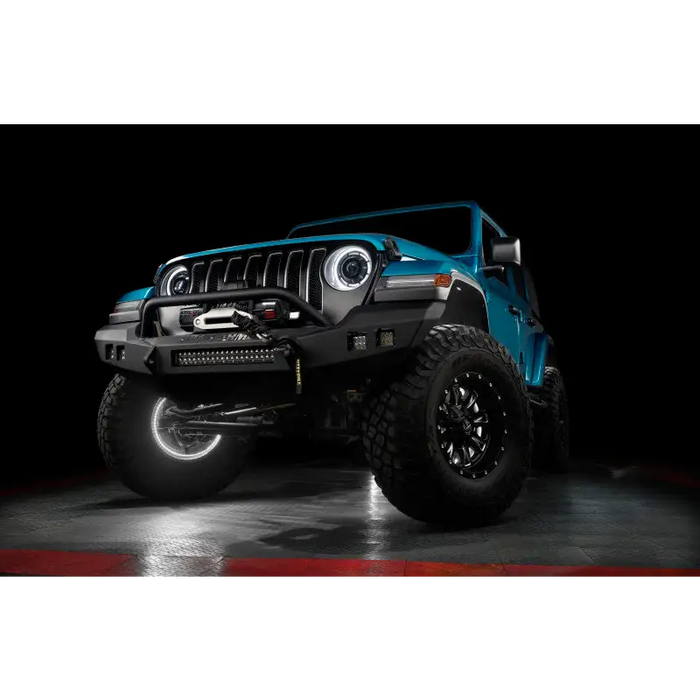 Close-up of blue Jeep illuminated by white rock lights against black background.