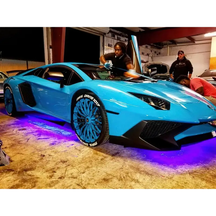 Blue sports car with person next to it, showcasing dynamic colorshift car lights - Oracle Universal Dynamic LED Underbody Kit.