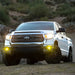 White truck driving down dirt road featuring Rigid 360-Series 4in LED SAE J583 fog light kit.