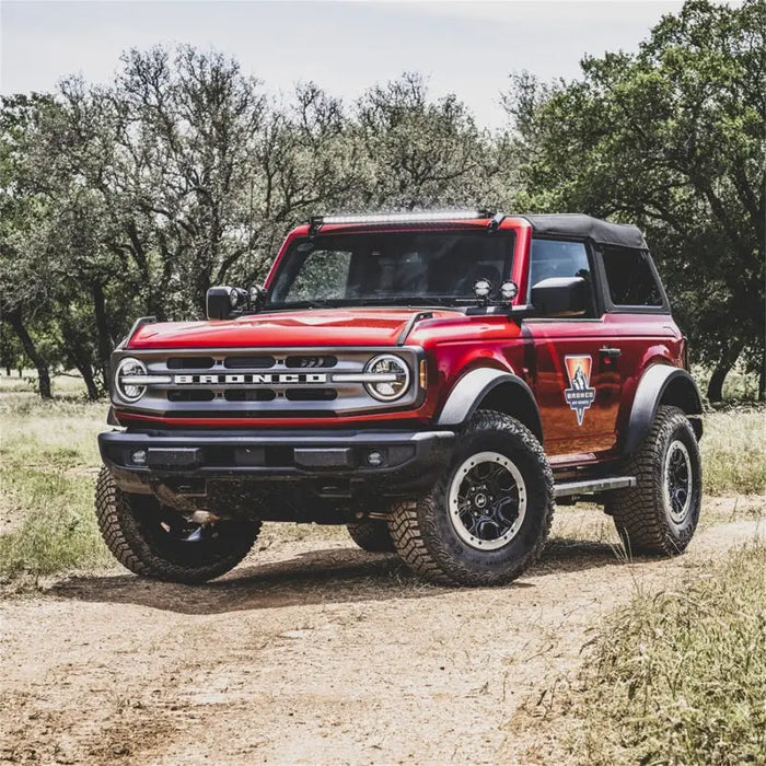 Red truck driving down dirt road with Rigid Industries fog light kit installed.