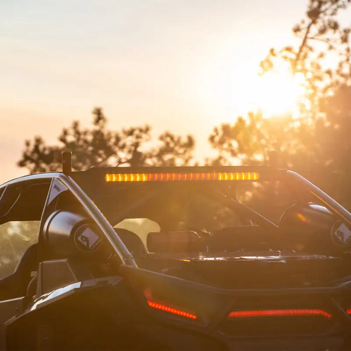 Black car with sun shining behind it, featuring Rigid Industries 28in Rear-Facing Chase Light Bar.