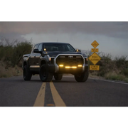 Rigid Industries 360-Series 4in Fog with Amber PRO Lens truck driving down road with sign in background.