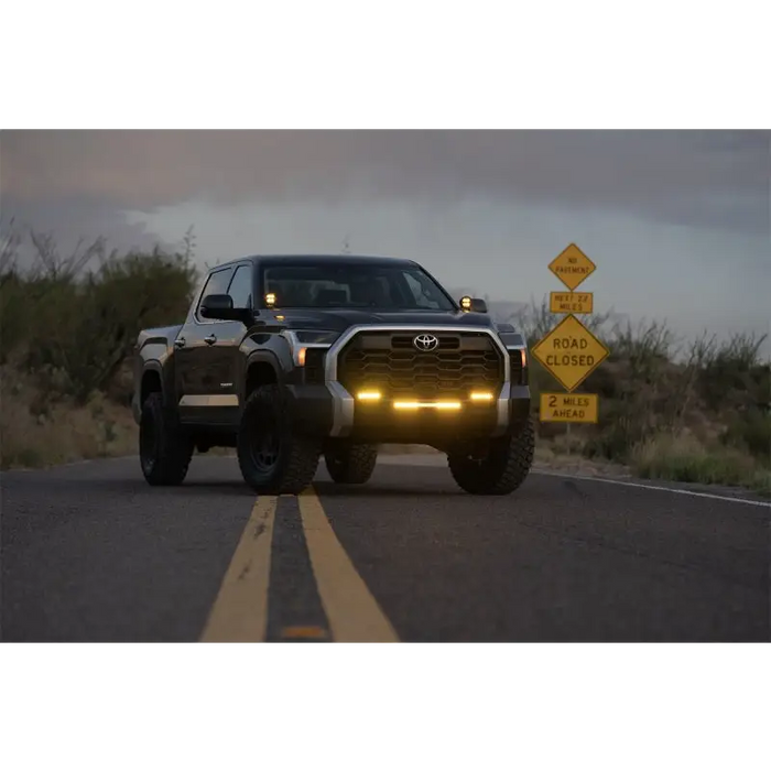 Rigid Industries 360-Series 4in Fog with Amber PRO Lens truck driving down road with sign in background.