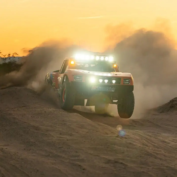 Rigid Industries 360-Series Laser 6in Amber Backlight truck driving on a dirt road at sunset