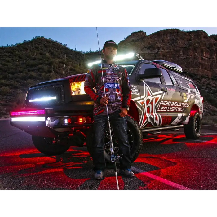 Man standing next to Cool White Rigid Industries Rock Light Kit truck.