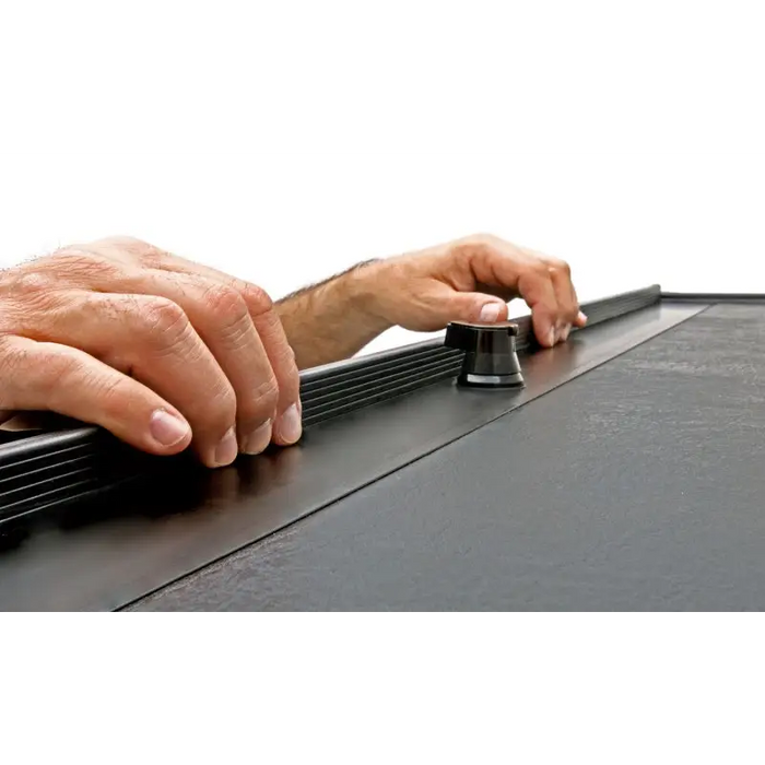 Roll-N-Lock truck bed cover: Man’s hand holding black plastic sheet.