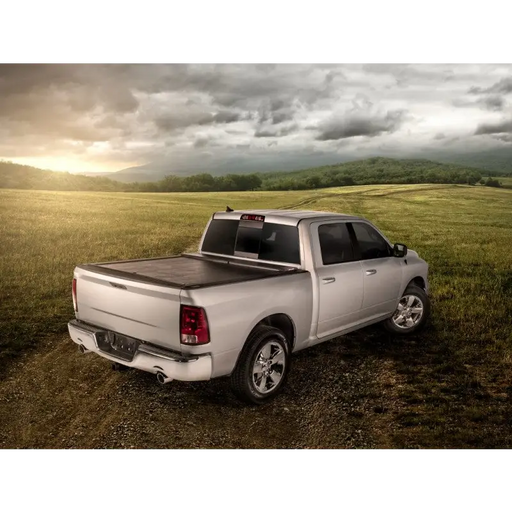 Roll-N-Lock truck bed cover on Toyota Tacoma in field under cloudy sky