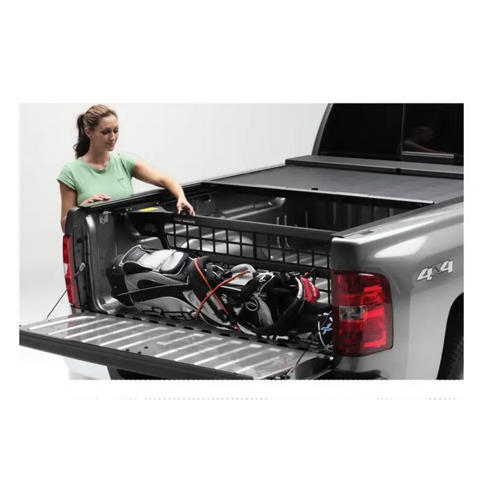 Woman loading truck bed with tool in Roll-N-Lock Toyota Tacoma Cargo Manager