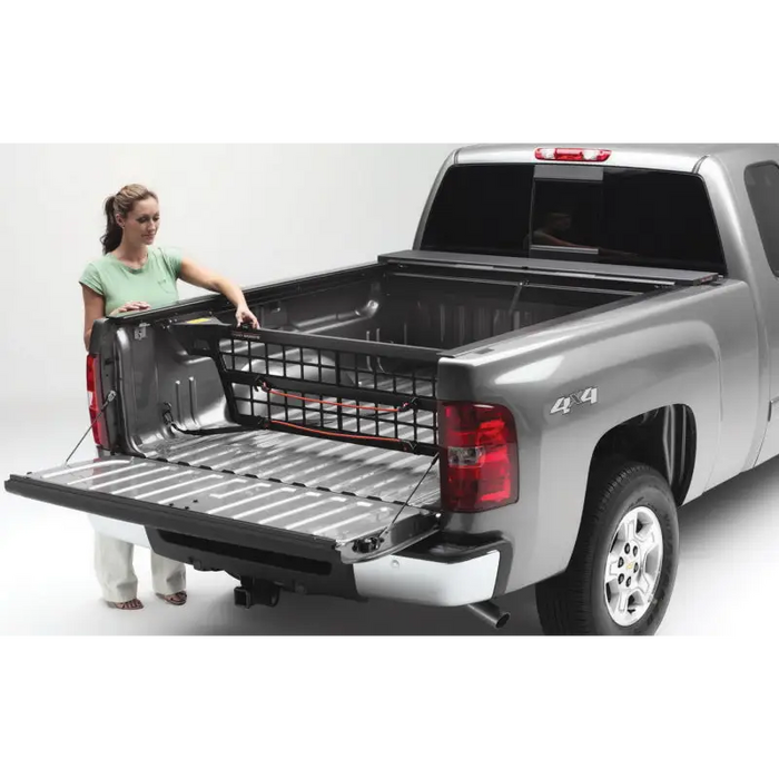 Woman loading Roll-N-Lock Cargo Manager in Toyota Tacoma truck bed