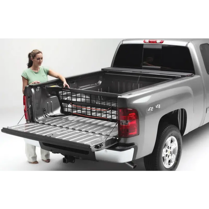 Woman loading truck bed with Roll-N-Lock Cargo Manager on 16-18 Toyota Tacoma Crew Cab SB.