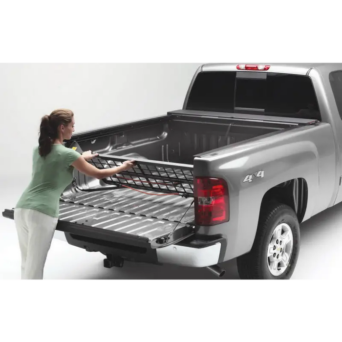 Woman loading truck bed with Roll-N-Lock Cargo Manager for Toyota Tacoma Crew Cab SB.