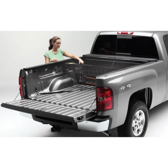 Woman loading bed of truck with Roll-N-Lock Cargo Manager for Toyota Tacoma.