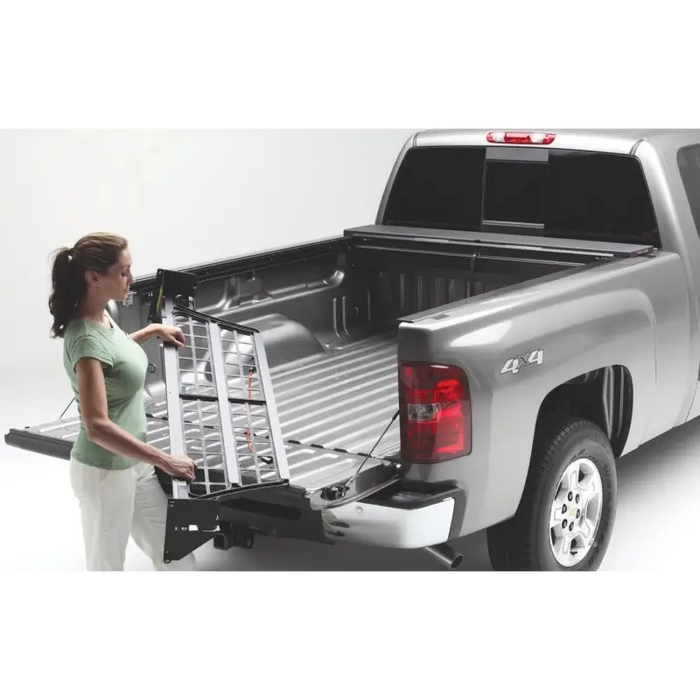 Woman loading Roll-N-Lock Toyota Tacoma Cargo Manager in truck bed