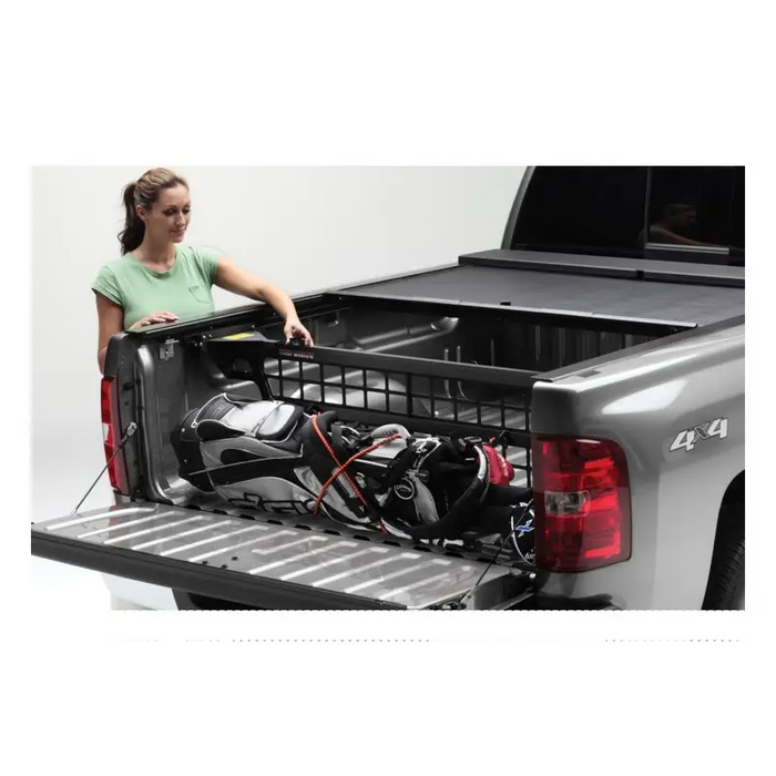 Woman loading truck bed with Roll-N-Lock Cargo Manager in Toyota Tacoma.