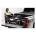 Woman loading truck bed with Roll-N-Lock Cargo Manager in Toyota Tacoma.
