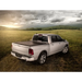 Roll-N-Lock retractable tonneau cover on a truck bed parked in a field under a cloudy sky