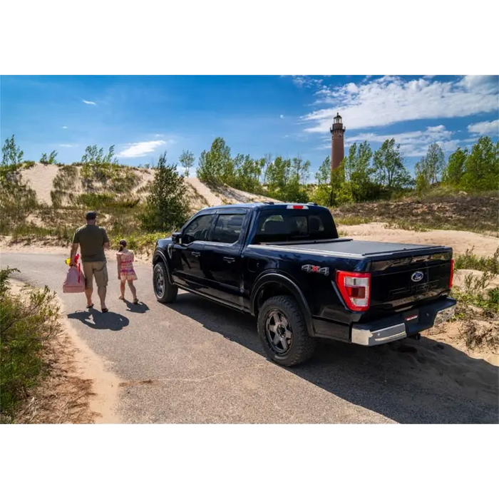 Father and daughter walking towards black truck with Roll-N-Lock 16-18 Toyota Tacoma Crew Cab SB M-Series Retractable Tonneau Cover.