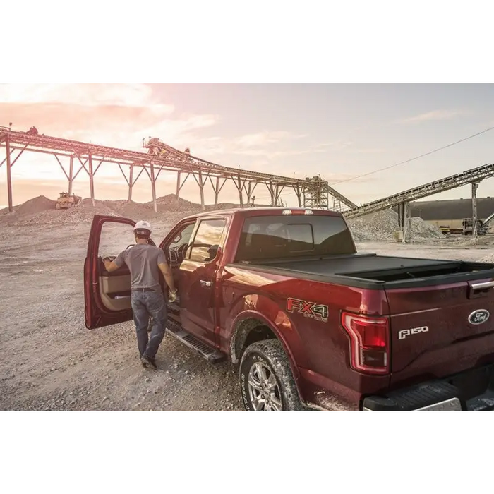 Man loading gravel onto truck bed with Roll-N-Lock A-Series Retractable Tonneau Cover