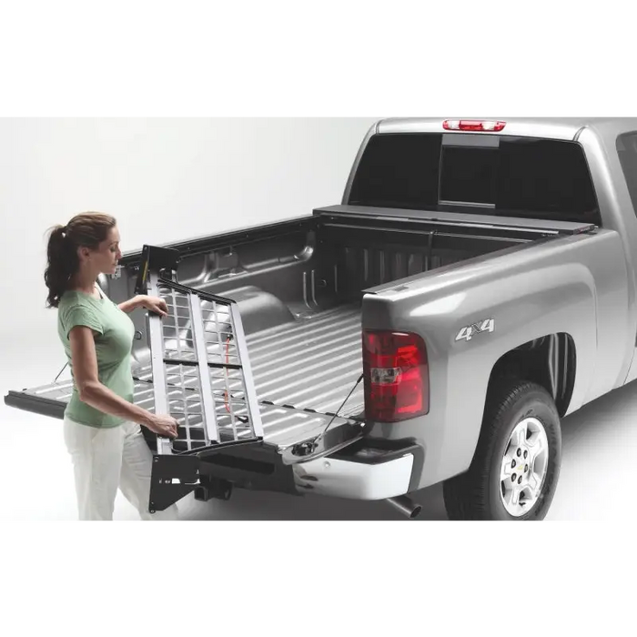 Woman loading Roll-N-Lock Cargo Manager in Jeep Gladiator truck bed